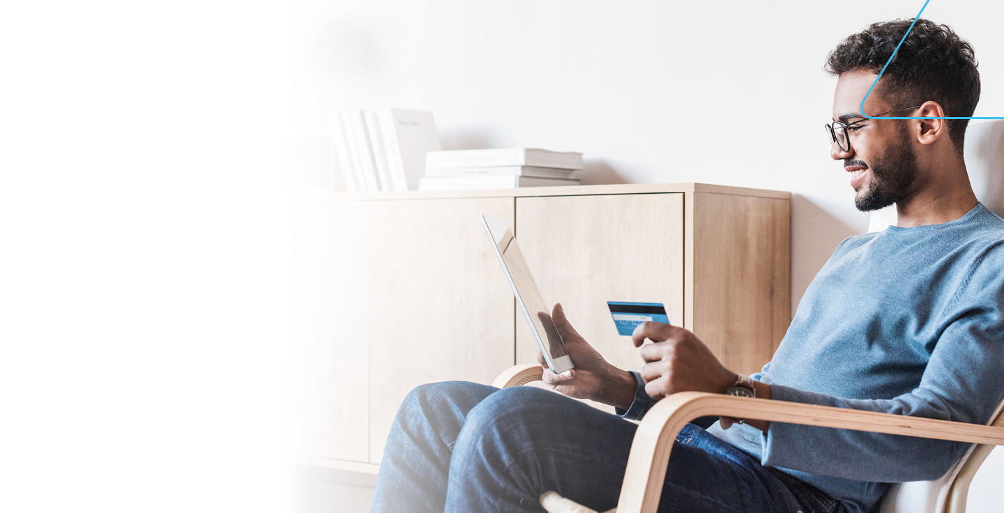 Foto de homem sentado com um tablet e o carto Banrisul